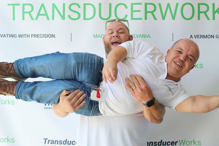 Two corporate event guests turning their height difference into a playful photo booth pose