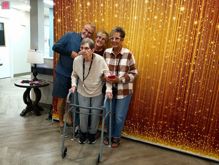 Guest using a walker joining adults for a group photo