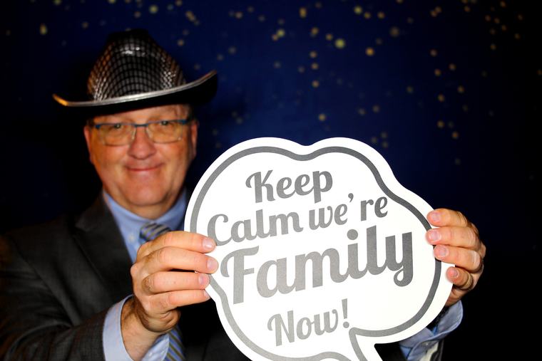 Wedding guest posing with a Keep Calm We're Family Now photo booth prop