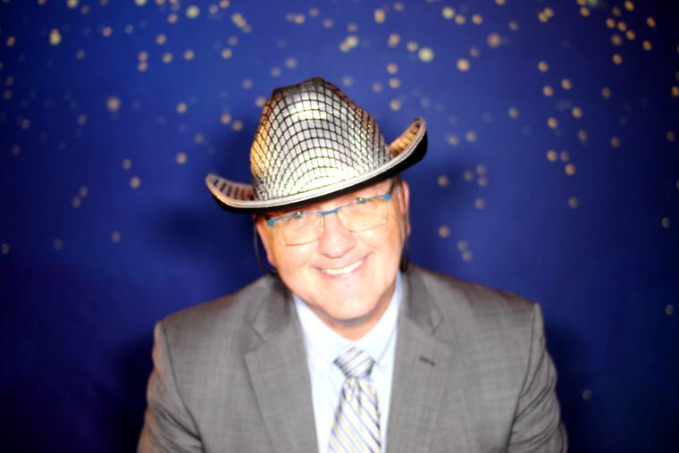 Wedding guest smiling at the photo booth camera in a cowboy hat