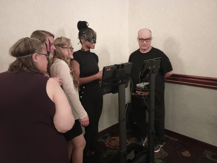 Guests smiling together as they gather around a screen to watch their raw drone video